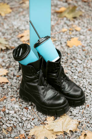 Slender female feets in military boots. street photo. Two blue paper coffe cupsの写真素材
