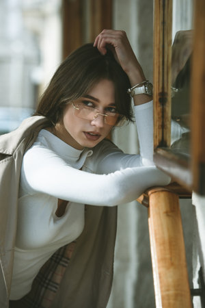 beautiful brunette girl in a sunglasses dressed in white blouse and beige coat. Stylish trendy...