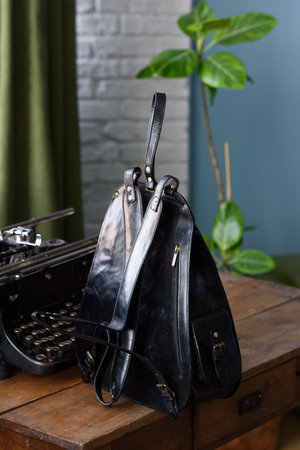 Black leather casual backpack on a wooden tableの写真素材