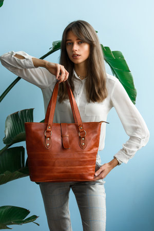 close-up photo of orange leather bag in a womans handsの写真素材
