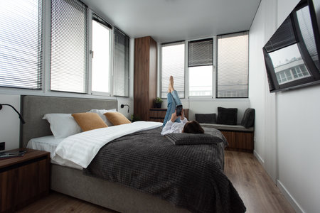 Woman with a phone on a bed in modern apartmentの写真素材