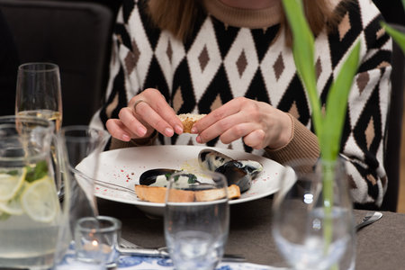woman going to eat mussels in white wine sauce and white bread toasts in a restaurantの写真素材