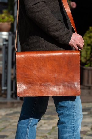 close-up photo of light brown messanger leather bag on mans shoulderの写真素材