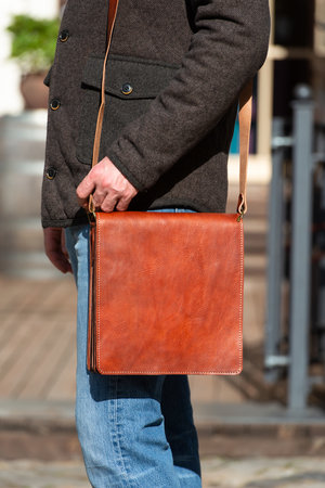 close-up photo of light brown messanger leather bag on mans shoulderの写真素材