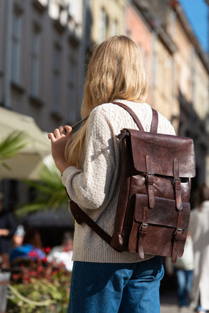 Part photo of a woman with a brown leather backpack with antique and retro look. Outdoors photoの写真素材