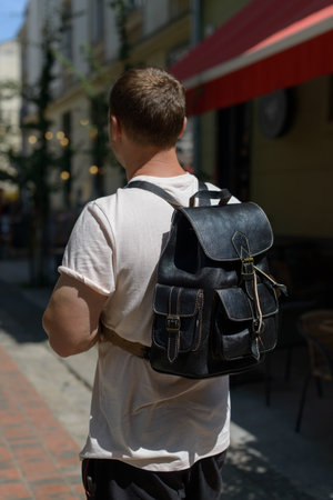 Part photo of a man with a black leather backpack with antique and retro look. Outdoors photoの写真素材