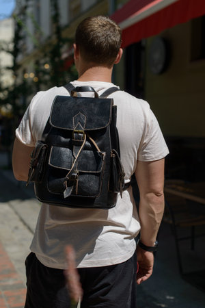Part photo of a man with a black leather backpack with antique and retro look. Outdoors photoの写真素材