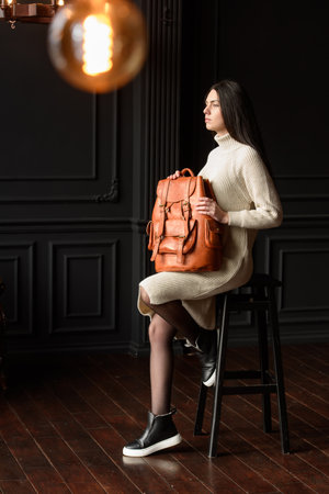 photo of a woman with a orange leather backpack with antique and retro look. indoors photoの写真素材