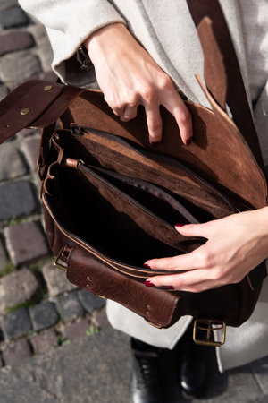 photo of a woman opening a brown leather briefcase with antique and retro look. Outdoors photoの写真素材