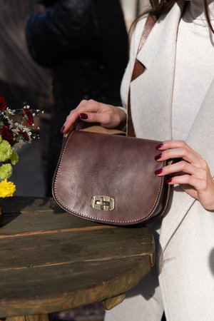 photo of a womans hyands with a brown leather handbag with retro look. Outdoors photoの写真素材