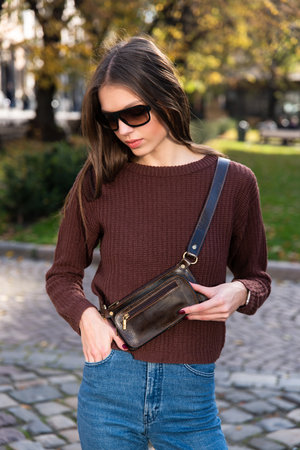 photo of a small brown leather belt bag on a girl. street photoの写真素材