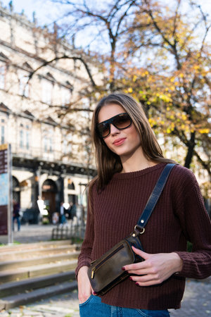 photo of a small brown leather belt bag on a girl. street photoの写真素材