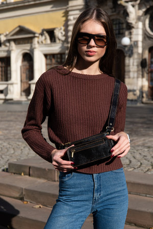 photo of a small dark brown leather belt bag on a girl. street photoの写真素材