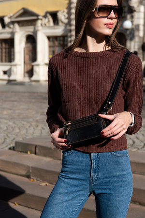 photo of a small dark brown leather belt bag on a girl. street photoの写真素材