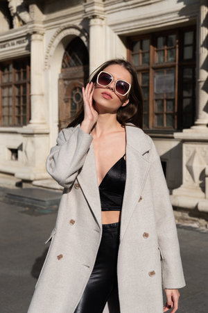 Street style, autumn, spring fashion concept: fashionable woman wearing luxury beige coat, a top with razors and sunglassesの写真素材