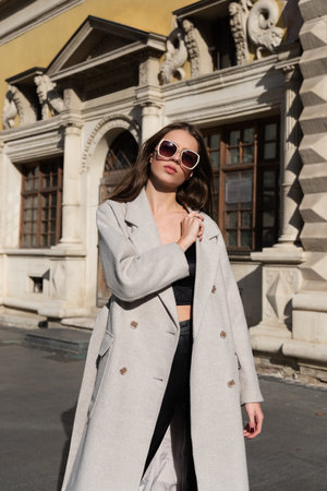 Street style, autumn, spring fashion concept: fashionable woman wearing luxury beige coat, a top with razors and sunglassesの写真素材