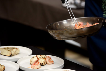 chef in the restaurant prepares saganaki, traditional Greek cheese snack that is fried in a pan or...