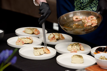 chef in the restaurant prepares saganaki, traditional Greek cheese snack that is fried in a pan or grilledの写真素材