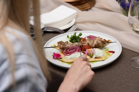 woman eats in a restaurant souvlaki with pita and tzatziki sauceの写真素材