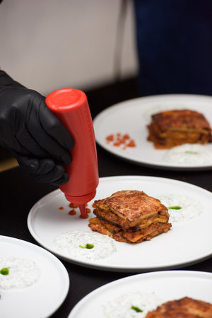 the chef in the restaurant preparing traditional greek moussaka in white plate on black tablecloth backgroundの写真素材