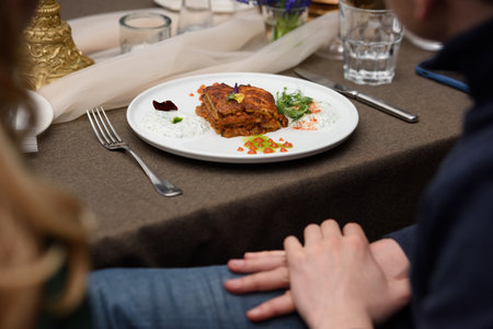 portion of traditional greek moussaka in white plate on a table in a restaurantの写真素材