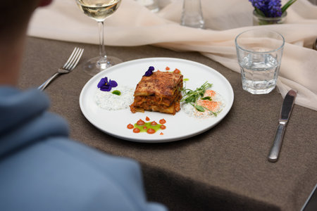 portion of traditional greek moussaka in white plate on a table in a restaurantの写真素材