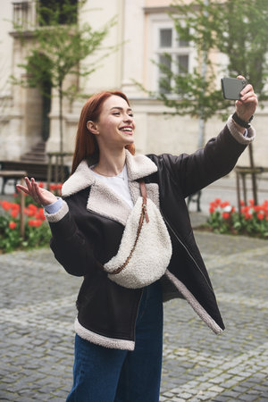happy woman communicates with friends via video link outdoors on an old town streetの写真素材
