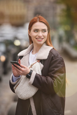happy woman communicates with friends via video link outdoors on an old town streetの写真素材