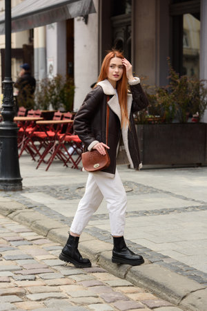 a red-haired girl in a leather jacket. cheerful woman with long red hair poses for a photographerの写真素材
