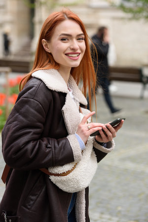 happy woman communicates with friends via video link outdoors on an old town streetの写真素材