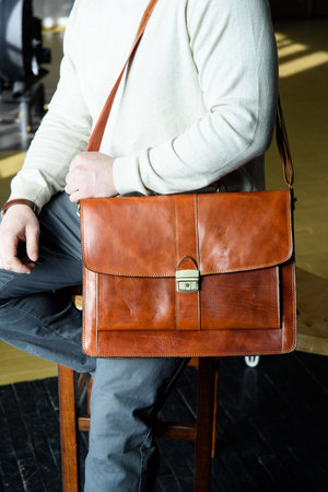 Part photo of a man with a orange leather briefcase with antique and retro look. indoors photoの写真素材