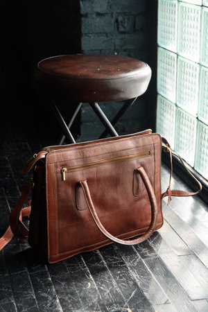 close-up photo of light brown leather briefcase on a black wooden floor.の写真素材