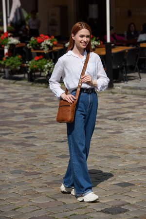 photo of a woman with a small brown leather bag.の写真素材