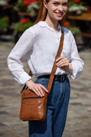 photo of a woman with a small brown leather bag.の写真素材
