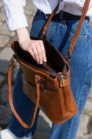 woman opening small light brown womens leather bagの写真素材