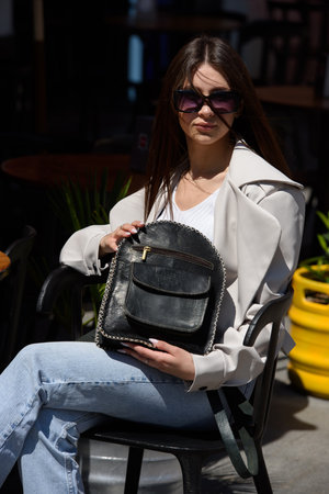 Part photo of a woman with a black leather backpack with antique and retro look. Outdoors photoの写真素材