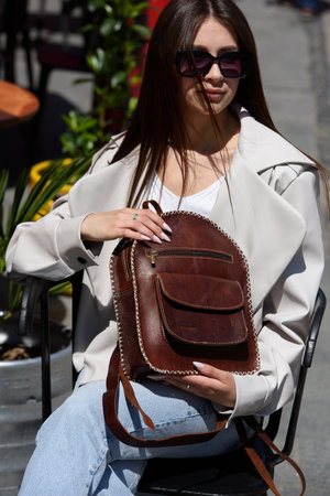 Part photo of a woman with a brown leather backpack with antique and retro look. Outdoors photoの写真素材