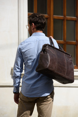 Handsome businessman walking on the street, with luxury brown leather briefcase. Fashionable style.の写真素材