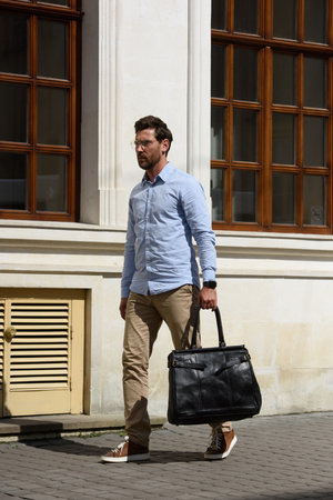 Handsome businessman walking on the street, with luxury black leather briefcase. Fashionable style.の写真素材
