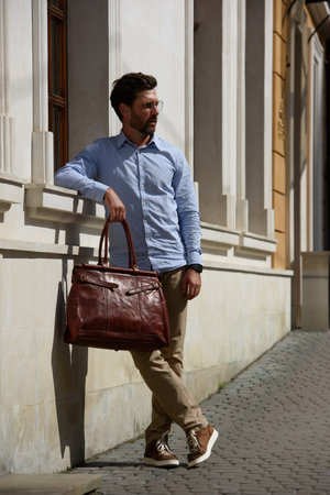 Handsome businessman walking on the street, with luxury leather briefcase. Fashionable style.の写真素材