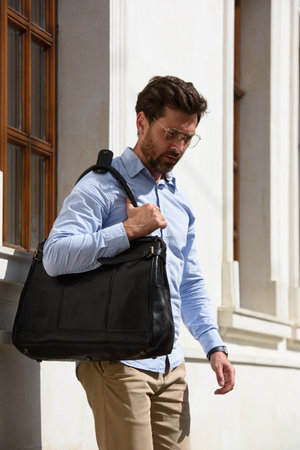 Handsome businessman walking on the street, with luxury black leather briefcase. Fashionable style.の写真素材