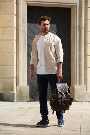 Handsome businessman walking on the street, with luxury leather dark brown backpack. Fashionable style.の写真素材