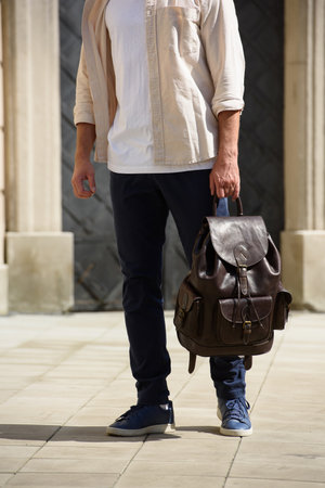 Handsome businessman walking on the street, with luxury leather dark brown backpack. Fashionable style.の写真素材