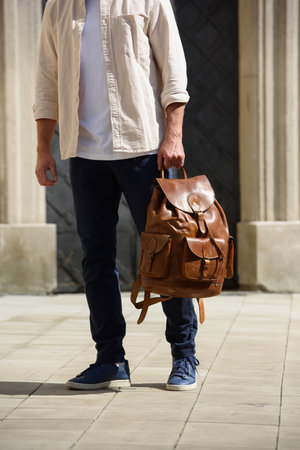Handsome businessman walking on the street, with luxury leather brown backpack. Fashionable style.の写真素材