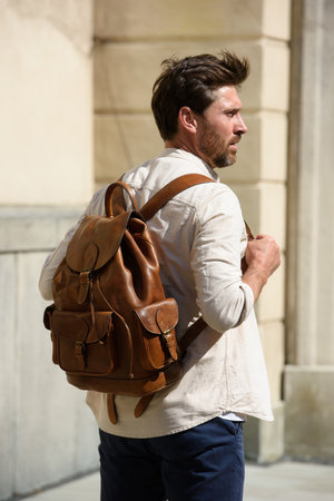 Handsome businessman walking on the street, with luxury leather brown backpack. Fashionable style.の写真素材