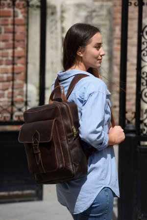 Beautiful young girl wearing blue jeans, shirt and white t-shirt posing with brown leather backpackの写真素材