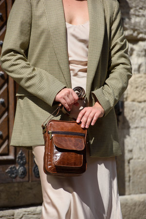 pretty girl in satin long dress and checkered jacket posing with leather handbag outsideの写真素材