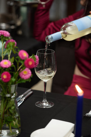 white wine is poured into a glass in a restaurantの写真素材
