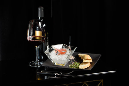 salmon fish caviar, on ice, with croutons, lemon, on a transparent dish, on a dark backgroundの写真素材