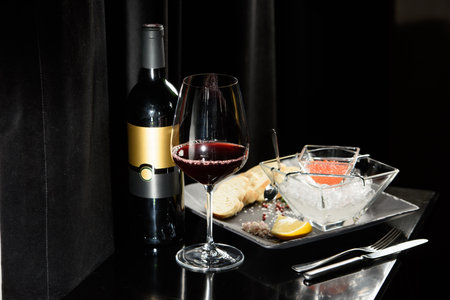 salmon fish caviar, on ice, with croutons, lemon, on a transparent dish, on a dark backgroundの写真素材